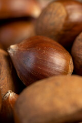 a hard edible chestnut fruit in a brown shell on a wooden table, a group of raw fruits of chestnut with a hard shell of brown color