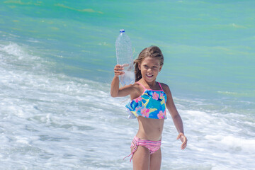 A child playing in the sea with an empty plastic bottle