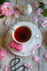 A cup of aromatic tea, a book and a rose on the table.