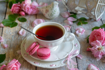 A cup of aromatic tea, a book and a rose on the table.
