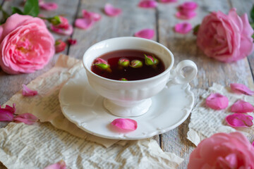 A cup of aromatic tea, a book and a rose on the table.