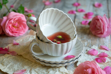 A cup of aromatic tea, a book and a rose on the table.