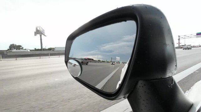 camera capturing reflection in the side rear-view mirror car speeds along the highway