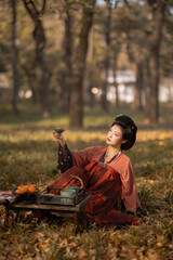 A woman enjoying tea in a beautiful outdoor setting wearing a colorful traditional dress.