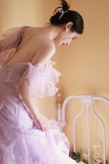 Profile of a woman in a flowing lavender dress, standing gracefully in a cozy indoor setting.