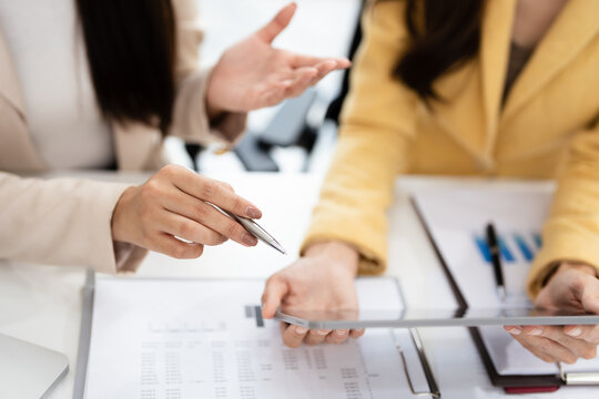 Business partners working with analysis report and advisor showing plan, Two businesswoman working with Financial analysts reports and planning investment at office. - Powered by Adobe