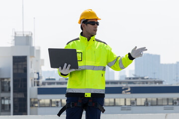 Engineer inspecting solar panels using laptop on rooftop