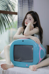 A woman relaxing indoors with a vintage-style television and a serene atmosphere.
