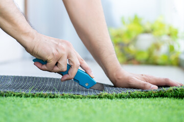Close-up of man hand cutting and installing artificial grass