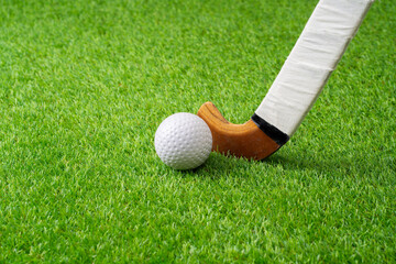 Close up of hockey player, stick and ball on artificial turf.