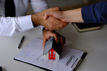 The real estate agent and the customer shaking hands while selling the property