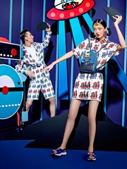 Models in trendy outfits playing in a colorful studio setting with a playful atmosphere.