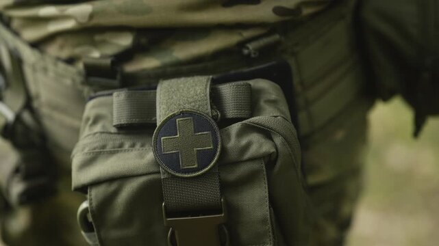 Camouflaged army soldier on a stealth mission. Close-up on the military equipment with a first aid kit
