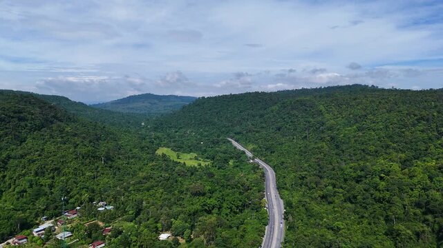 Drone footage of the aerial view of a winding road cutting through lush green forest. Scenic highway number 304 in Thailand links the Bangkok area to Nakhon Ratchasima in the northeastern region