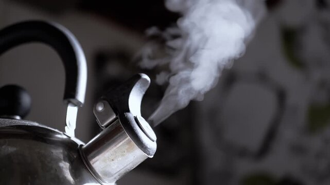 Close up, Whistling Metal Boiling Old Kettle on Stove in Kitchen. Retro kettle with rising steam in rays of sunlight. Steam texture on a blurred background. Vintage video. Cozy atmosphere. Morning.