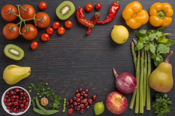 Fresh colorful assortment of fruits and vegetables including tomatoes, kiwi, bell peppers, berries, and greens on a dark wooden background, promoting healthy eating, organic living, and vibrant nutrit