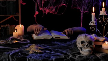 A scary zombie hand flips through a book