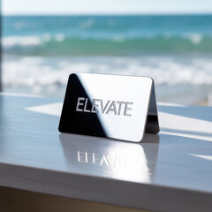 Polished metal sign with the word ELEVATE reflects on a tabletop with an ocean backdrop