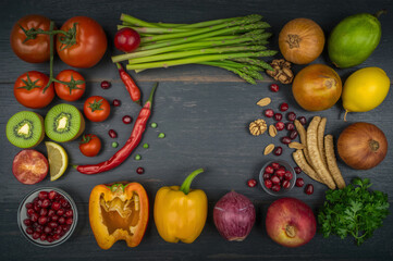 Fresh colorful assortment of fruits and vegetables including tomatoes, kiwi, bell peppers, berries, and greens on a dark wooden background, promoting healthy eating, organic living, and vibrant nutrit