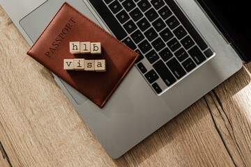 H1B visa wooden blocks on passport and laptop, symbolizing U.S. work permit