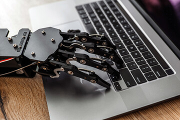 Robotic hand typing on laptop keyboard, concept of artificial intelligence and automation