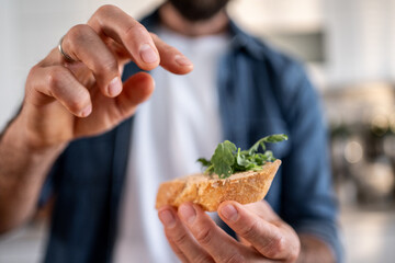 Man preparing healthy appetizer food with arugula on bread