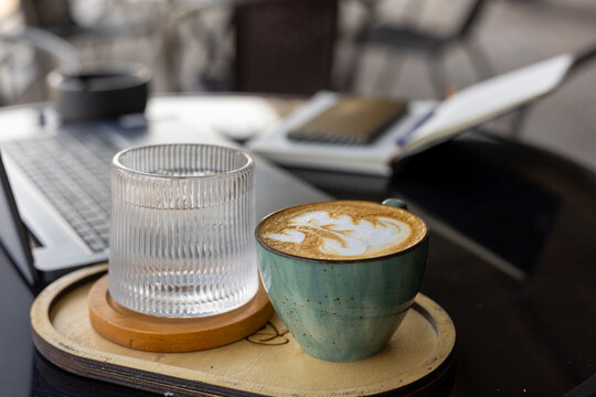 Cup of coffee and laptop on table in cozy cafe setting - Powered by Adobe
