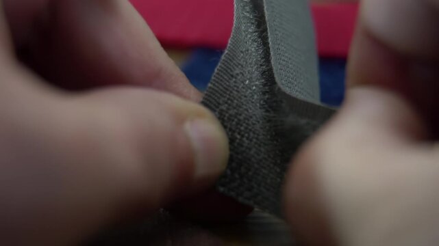 A hook-and-loop fastening system (Velcro) during the process of being separated by a person.