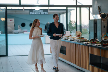 A couple enjoying breakfast at a hotel open buffet, selecting fresh food in a bright and relaxed holiday atmosphere. Perfect for themes of travel, hospitality, and vacation lifestyle. © ALPSARAL