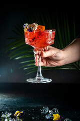 Elegant red cocktail with floral garnish in a crystal glass