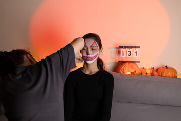 Woman is applying makeup to her face for what appears to be a Halloween 