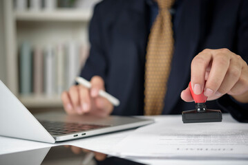 Close up of hand stamping approved seal on financial document. Notary public or lawyer certifying...