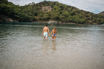 A couple enjoying time together at the beach, walking along the shoreline and embracing a relaxed summer holiday atmosphere by the sea.