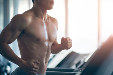 Shirtless athletic Asian man running on treadmill in gym, sunlight streaming through window, focused and determined expression, fitness and healthy lifestyle concept