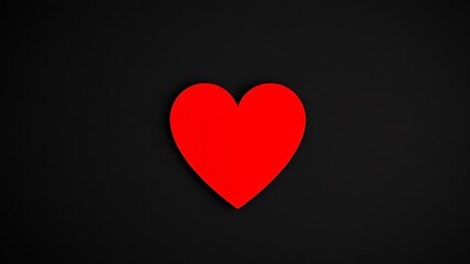 Fototapeta premium A red heart shape stands out against a textured black background with warm lighting.