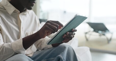 Hands, tablet and black man in home with research for education, learning or college application. Relax, planning and African male person with digital technology for student loan in apartment. - Powered by Adobe