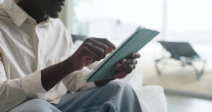 Hands, tablet and black man in home with research for education, learning or college application. Relax, planning and African male person with digital technology for student loan in apartment.