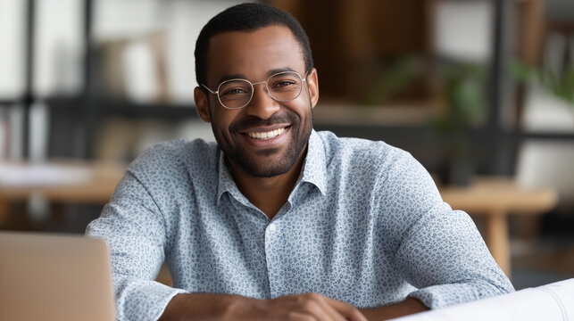 Smiling male project manager with blueprints and computer on table sharing ideas with coworkers while collaborating in meeting | project management blueprint planning team