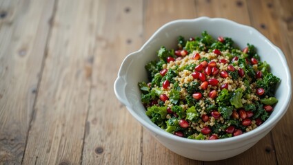 Nutritious Kale and Quinoa Salad with Pomegranate Seeds in a White Bowl on a Wooden Table