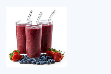 Three glasses of dark red smoothie with straws with vast copy spcae on the right, surrounded by fresh strawberries and blueberries on a white background.