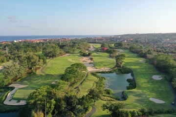 Obraz premium Beautiful golf course with pond and tiled roofs