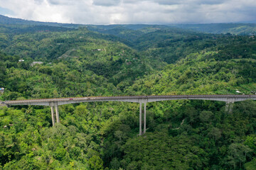 Long high bridge surrounded by green forests and mountains