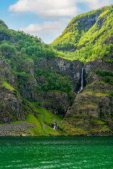 Sunlit panorama of Naeroyfjord with towering green mountains