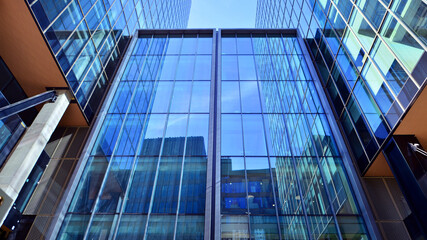 Obraz premium Bottom up view of modern glass office building. Commercial real estate. New commercial office building in modern city.