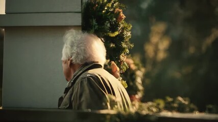 A man honors memories at a memorial, surrounded by flowers in a serene park as evening light falls