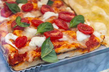 Fresh baked focaccia or pala romana pizza with vegetables, pepperone, mushrooms, tomatoes and cheese in bakery in Parma, Emilia Romania, Italy