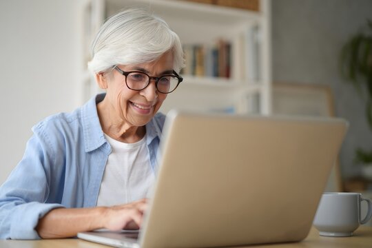 Senior woman using laptop for online communication and social media use - Powered by Adobe