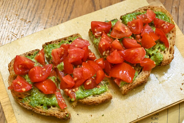 Starter in italian restaurants, bread bruschetta roasted homebaked bread with olive oil and chopped ripe tomatoes and pesto