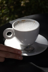 Drinking of italian coffee cappuccino served in cafe in Varenna, Como lake, Italy