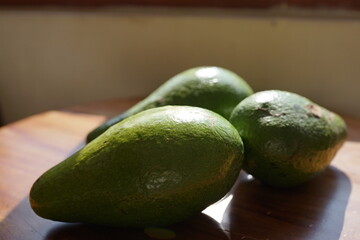Fresh green avocados arranged on a wooden surface, a healthy and delicious fruit